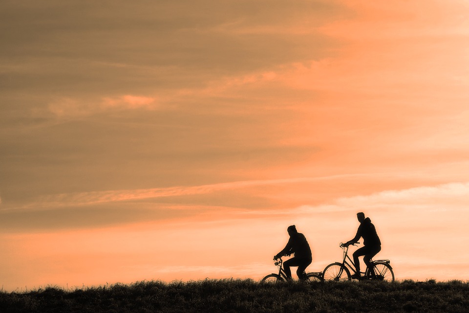 Two people riding bicycles under a sunset.